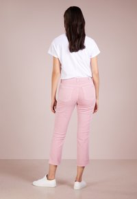 Pantaloni cropped rosa chiaro in denim, con design a cinque tasche e una leggera elasticità. Abbinati a una t-shirt bianca e sneakers bianche.