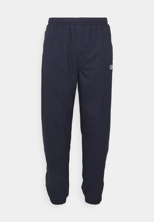 Marineblaue Jogginghosen aus leichtem Material mit elastischem Bund und Bündchen. Sie besitzen ein kleines Logo auf der Vorderseite.