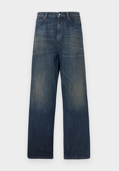 Jean denim bleu marine à jambe droite avec des zones délavées sur les cuisses et les poches avant, fermeture par bouton et passants pour ceinture.