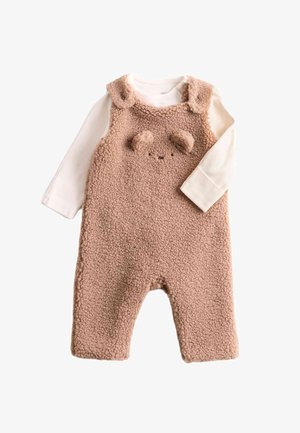 Beige fleece overall met een textuurafwerking, voorzien van een berengezichtontwerp, ronde oren en een bevestigd wit shirt met lange mouwen eronder.