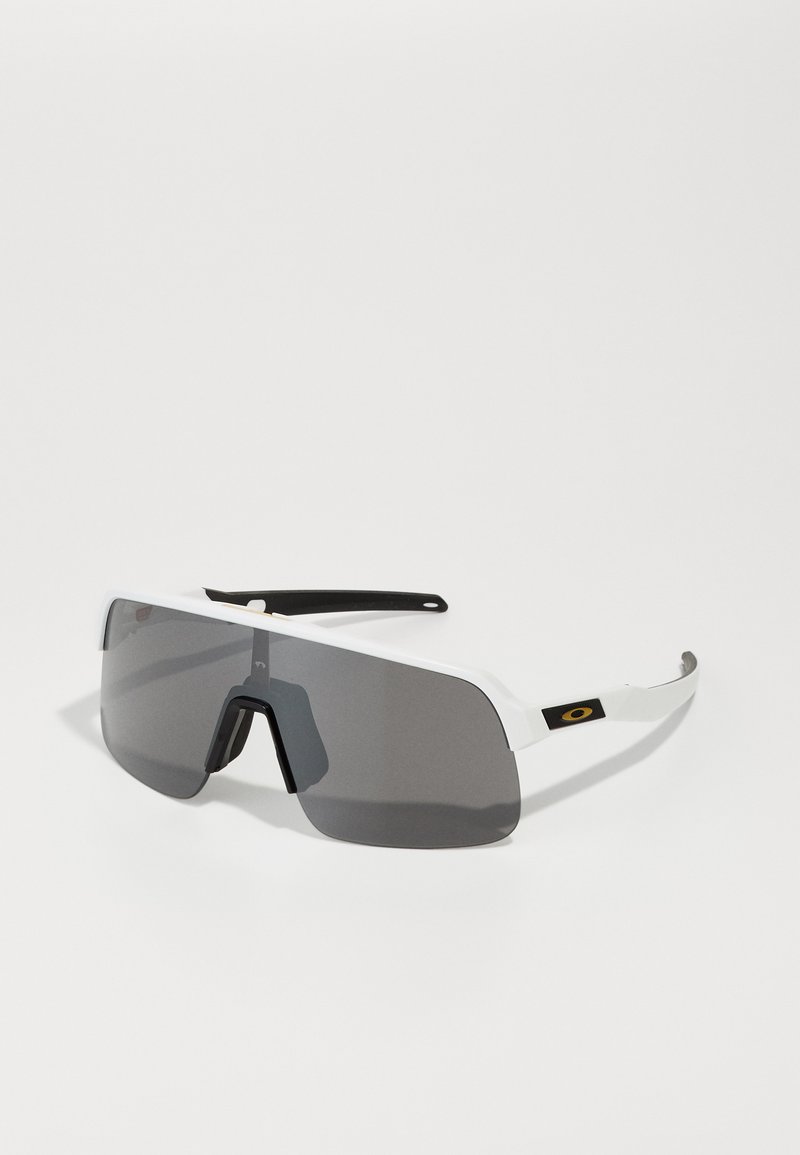 Gafas de sol blancas de gran tamaño con lentes grises, que presentan un acento negro en las patillas y un diseño angular. El material es plástico liviano.