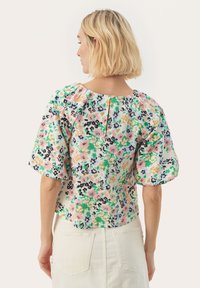 Bloemige blouse met korte mouwen en een ronde halslijn. Kenmerkt zich door een kleurrijk patroon van roze, groen en zwart op een lichte achtergrond. Sluiting met knoop aan de achterkant.