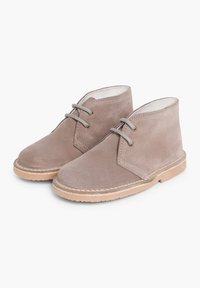 Stivaletti alla caviglia in suede grigio chiaro con punta rotonda, due occhielli per i lacci e suola in gomma beige; cuciture visibili lungo i bordi.