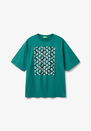 T-shirt en coton teal avec une coupe boxy, présentant un motif de feuilles noir et blanc au centre. Manches courtes et col rond.