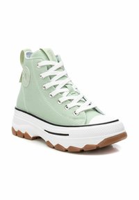 Zapatillas altas de lona verde claro con cordones blancos, una puntera de goma blanca y una suela de goma texturizada. Presenta un parche de logo en el lateral.