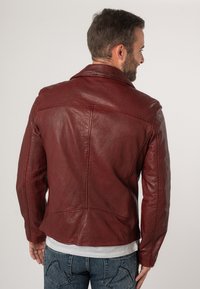 Giacca di pelle bordeaux con colletto classico, dettagli in cucitura visibili e design con tasca sul retro. Texture liscia e silhouette aderente.