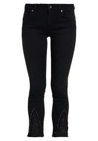 Svarta denimjeans med slim fit. Har spetsdetaljer och nitar vid fållen, vilket skapar ett unikt designelement.