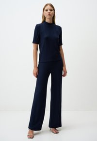 Marineblauw gebreid twee-delig outfit met een top met korte mouwen en een hoge halslijn, gecombineerd met wijde broekspijpen met een textuurpatroon.