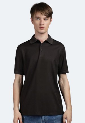 Polo nero con colletto e pattina a tre bottoni, maniche corte e una texture liscia, abbinato a jeans in denim blu.
