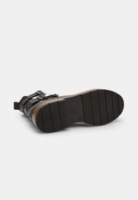 Stivaletto nero in pelle con cinturini regolabili, suola testurizzata e tacco in legno. La suola presenta scanalature orizzontali per una miglior aderenza.