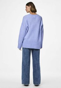 Verkeerd oversized lavendelkleurig sweater met geribbelde zoom en mouwen, gecombineerd met high-waisted, wijde jeans in een donkere denimwas.