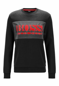 Felpa a maniche lunghe nera e grigia con un audace logo "BOSS" rosso sul petto. Realizzata in cotone con una finitura testurizzata.
