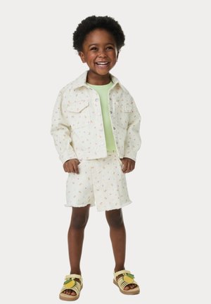 White denim jacket and shorts with colorful floral patterns, paired with a light green top and yellow sandals featuring a leaf accent.