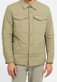 Lyse khaki-dunjakke med trykknapper, to brystlommer og sidelommer; har krave og syede paneler.