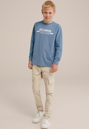 Sweatshirt bleu clair avec le texte "ATLANTA", associé à un pantalon cargo beige avec des poches latérales et des baskets blanches. Tissu lisse, design décontracté.