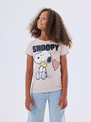 T-shirt en coton rose clair avec un graphisme noir et blanc de Snoopy, un cœur et le mot "love" en cursive. Coupe décontractée.
