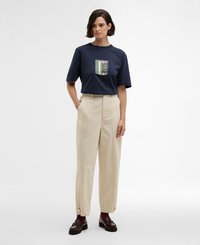 T-shirt de manga curta azul-marinho com um bolso e listras coloridas; combinado com calças de cintura alta em bege claro e mocassins pretos.