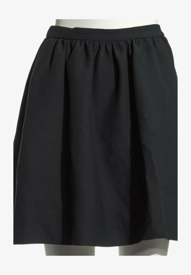 Jupe noire froncée avec large ceinture, longueur genoux sur un mannequin blanc.