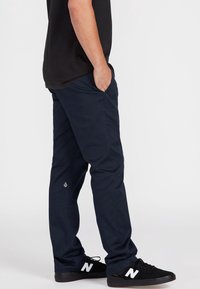 Marineblaue Hose aus leichtem Material, mit slim Fit, seitlichen Taschen und einem kleinen Logodetail am Saum.