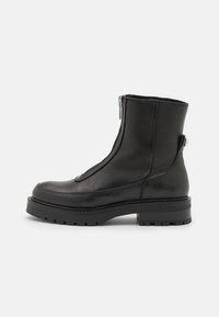 Stivali alla caviglia in pelle nera con zip laterale, finitura testurizzata, suola in gomma e tacco spesso, caratterizzati da elementi di design minimalisti.