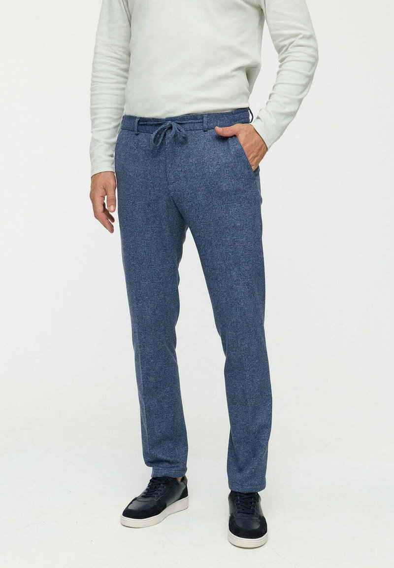 Donkerblauwe, gestructureerde pantalons met een tailleband met trekkoord, rechte snit, zijzakken en gecombineerd met zwarte sneakers.