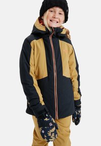 Zwarte en mosterdkleurige skijas met een capuchon, voorzien van contrasterende panelen en een oranje rits. Gepaard met gebloemde wanten en skibroek.