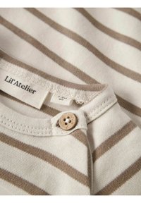 Camisa de algodón a rayas en color crema y marrón claro, con cuello redondo, detalle de botones de madera y etiqueta que dice "Lil'Atelier."