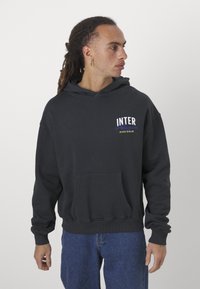 Sweatshirt preto com um bolso frontal, apresentando "INTER" em letras bold brancas e azuis no peito. Feito de tecido macio com um corte descontraído.