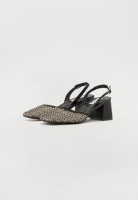 Mustat slingback-kengät, joissa on neliön muotoinen kärki, ja joissa on teksturoitu kudottu päällinen sekä matala lohkokorko. Säädettävä remmi, jossa on metallinen solki.