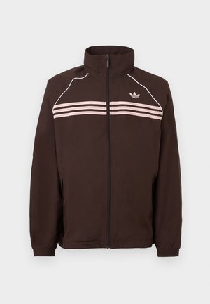 Brown zip-up jacket with high collar, light pink horizontal stripes, white piping on shoulders, and small Adidas logo on the chest.