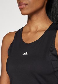 Schwarzes Sporttanktop mit rundem Ausschnitt, aus glattem Material, mit einem kleinen weißen Logo auf der linken Brustseite.