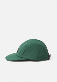 Dark green five-panel cap with a curved brim, embroidered patch on front, and adjustable strap at the back.