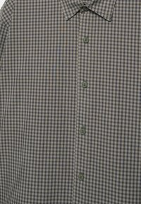 Herreskjorte med knapper, i et lille ternet mønster i brunt, blåt og hvidt, og med spids krave.