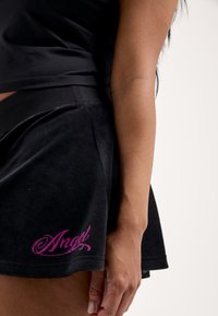 Μαύρο σκορτς από βελούδο με ελαστική μέση, φαρδιά γραμμή και ροζ κεντημένη λεπτομέρεια "Angel" στο τελείωμα. Μαλακή υφή.