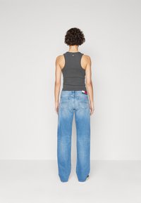 Gray tank top with wide-leg blue jeans. Jeans feature a faded wash and back pockets with red, white, and blue logo detail.