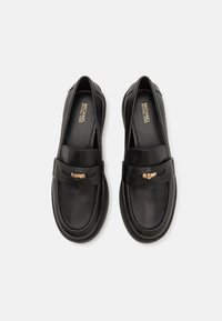 Black leather loafers with a smooth finish, featuring a gold-tone accent on the strap and a durable rubber sole. Simple, elegant design.