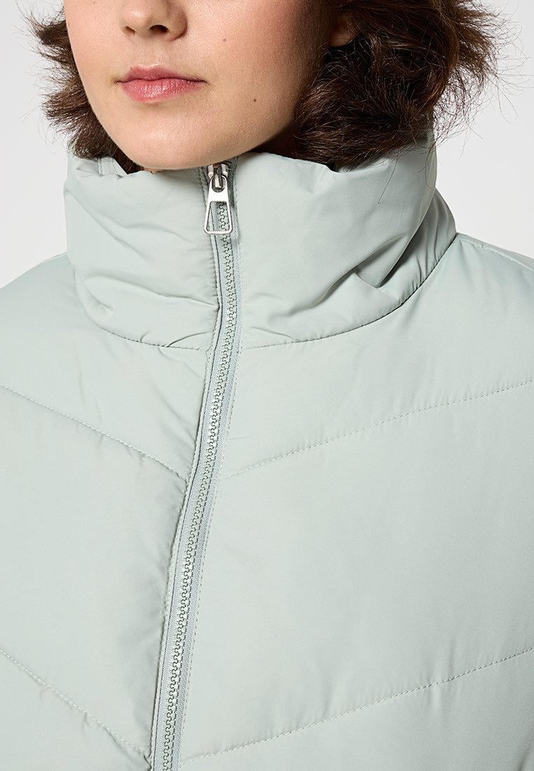 Padded jacket w kolorze jasnej mięty z wysokim kołnierzem, z suwakiem z przodu i szczegółami w kształcie zygzaka. Gładka tekstura.