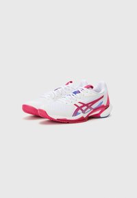 Hvide atletiske sko med en mesh-overdel, pink og blå detaljer, en tekstureret sål og fremtrædende lateral branding.