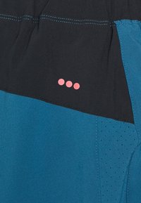 Pantalones cortos deportivos en azul y negro con una textura suave, que presentan acentos de puntos rosas y secciones perforadas para mayor transpirabilidad.