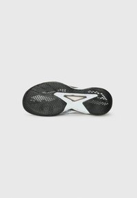 Sort og hvid atletisk sko sål med en tekstureret gummioverflade, der har et unikt geometrisk design og udskårne elementer for designdetalje.
