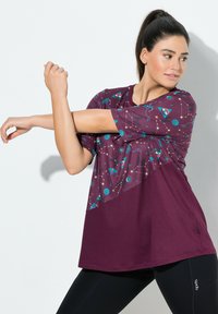 T-shirt sportif bordeaux avec un design graphique thématique spatial en bleu canard, comportant des étoiles, des planètes et des motifs de fusées. Manches courtes et coupe décontractée.