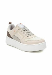 Zapatillas en color beige claro con parte superior de piel lisa, detalles en gris, cordones a juego y una gruesa suela de plataforma blanca. Presentan un diseño con perforaciones.