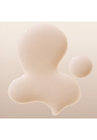 Crème beige clair avec une texture lisse et brillante ; présente une plus grande goutte avec une forme organique et une plus petite goutte ronde. L'arrière-plan est un doux dégradé.