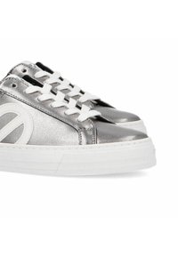 Metallic silver low-top sneakers with white laces and an oversized white logo accent. Rubber sole with textured pattern for grip.