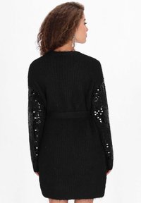 Czarny dzianinowy kardigan z długimi rękawami z ozdobami z cekinów. Posiada pasek do wiązania oraz teksturowane wykończenie, zapewniające komfortowe dopasowanie.