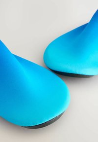 Blå skor med ett slätt, elastiskt material och en snygg design. Har en rund tå och en kontrasterande svart sula.
