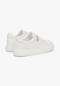 Białe skórzane sneakersy o gładkiej teksturze, zaokrąglonym nosku i białej gumowej podeszwie; mają mały zawieszkę z boku.