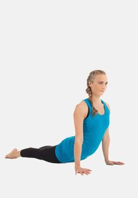 En blå atletisk linne och svarta leggings bärs av en person i yogaställning, med en texturerad tyg och åtsittande design.