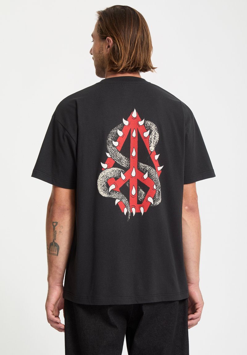 Czarny bawełniany t-shirt z odważnym, czerwono-białym wzorem graficznym przedstawiającym węża owiniętego wokół abstrakcyjnego kształtu.