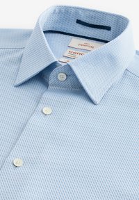 Himmelblaues Hemd mit einem strukturierten Muster, Button-Down-Kragen und weißen Knöpfen. Etiketten sind im Kragen sichtbar.